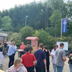Auf dem Bild sind mehrere Personen auf einem Fest zu sehen. Im Hitnergrund ist ein Dosenwurfstand und eine Zielscheibe für Bogenschießen zu erkennen.